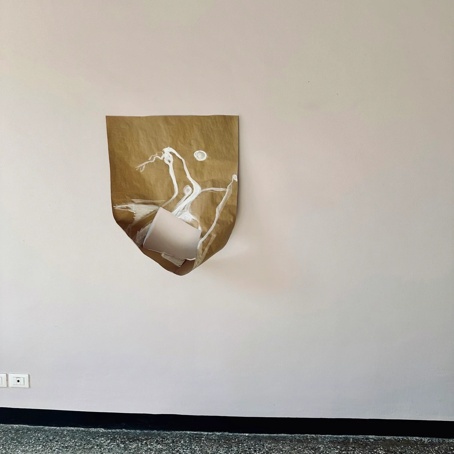 A brown paper work with white cutout shapes on a wall.