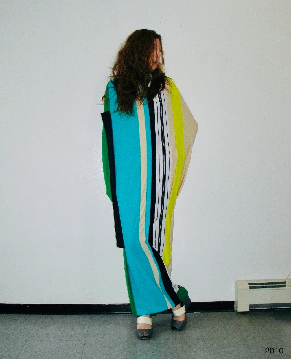 A person wearing a long turquoise, black and yellow striped garment.