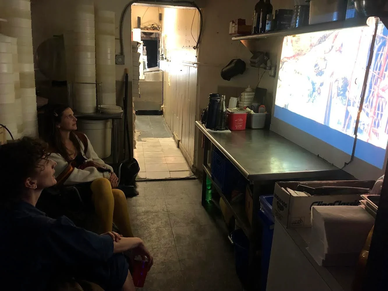 Seated visitors watching a projection near the shop counter.