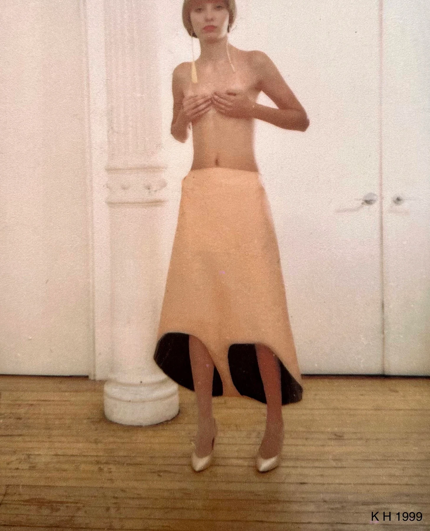 A person in a peach skirt with curved cutouts along the hem.