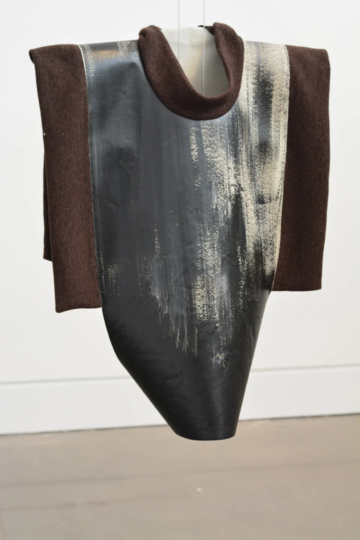 A dark sleeveless garment with a curved lower edge.