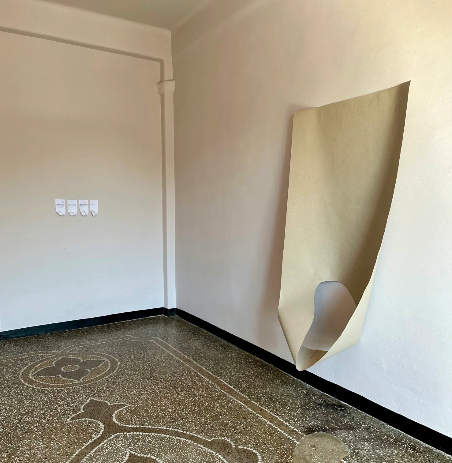 A large folded sheet hanging on a white wall.