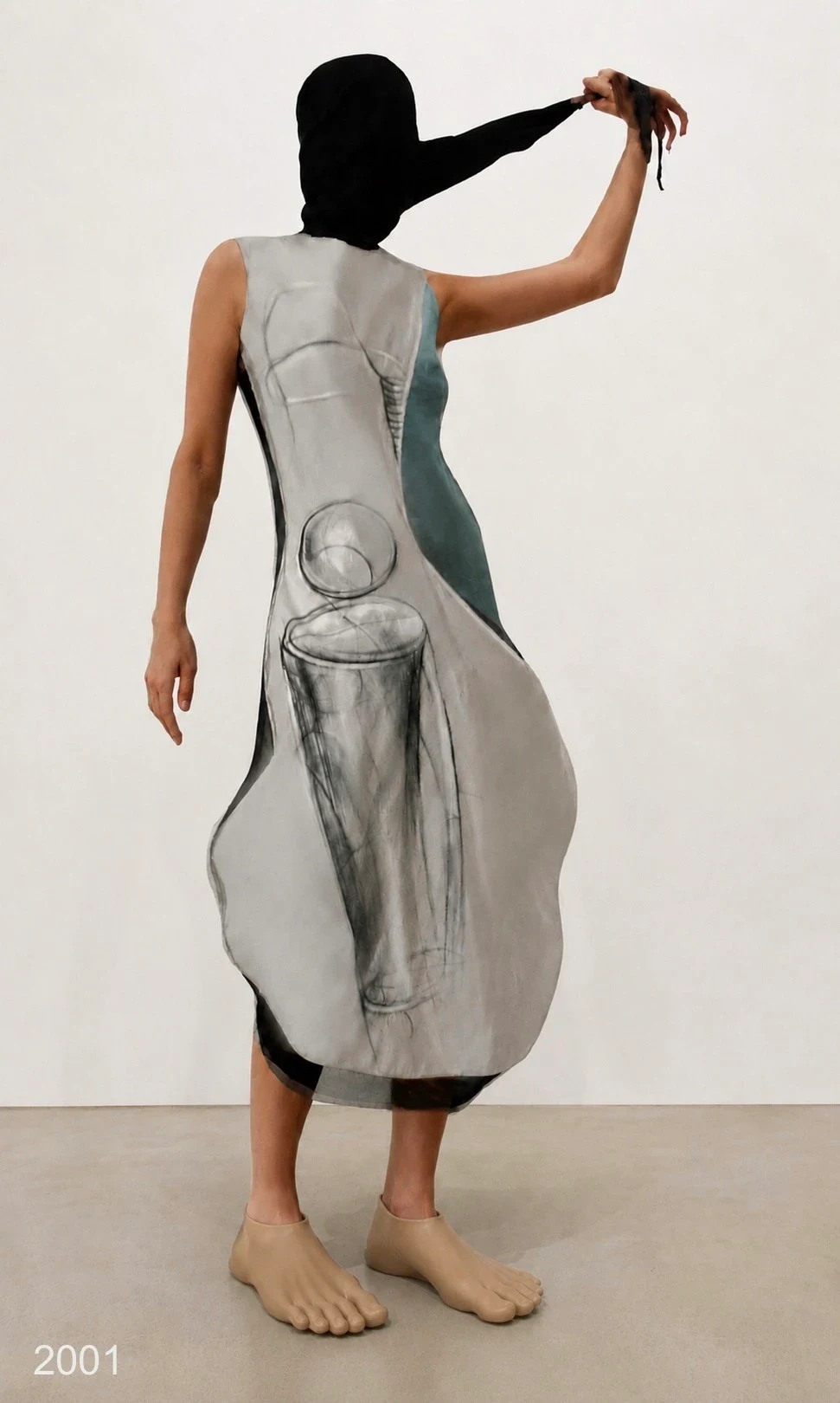 A person holding up part of a loose gray printed dress.