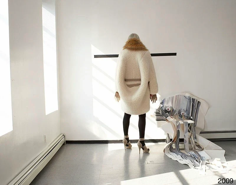 Sculptural cream and striped garments displayed in a sunlit room.