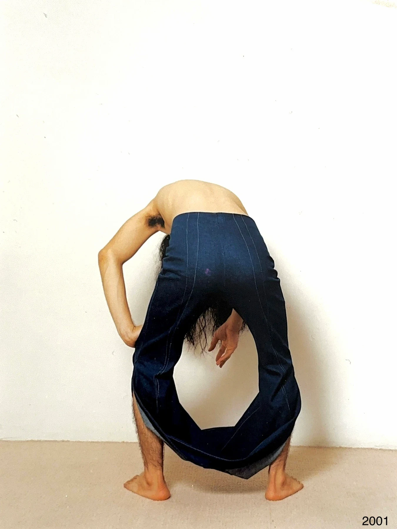A person bent forward wearing dark trousers with a large opening.