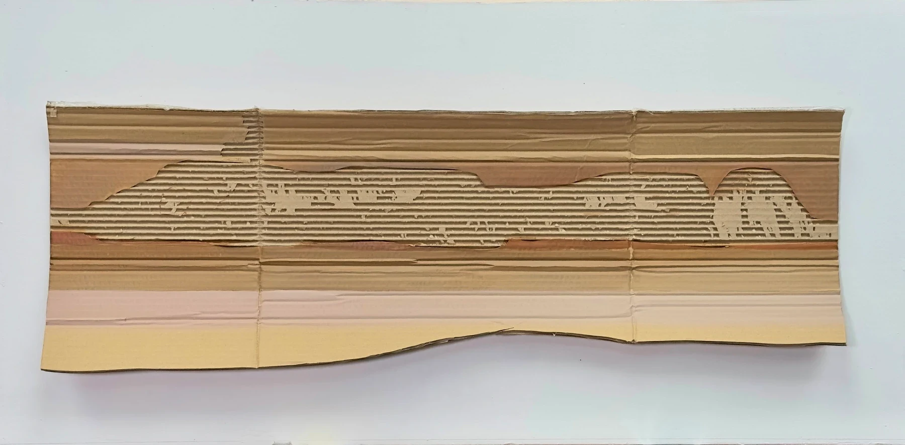A long layered cardboard work in brown, beige and pale yellow.