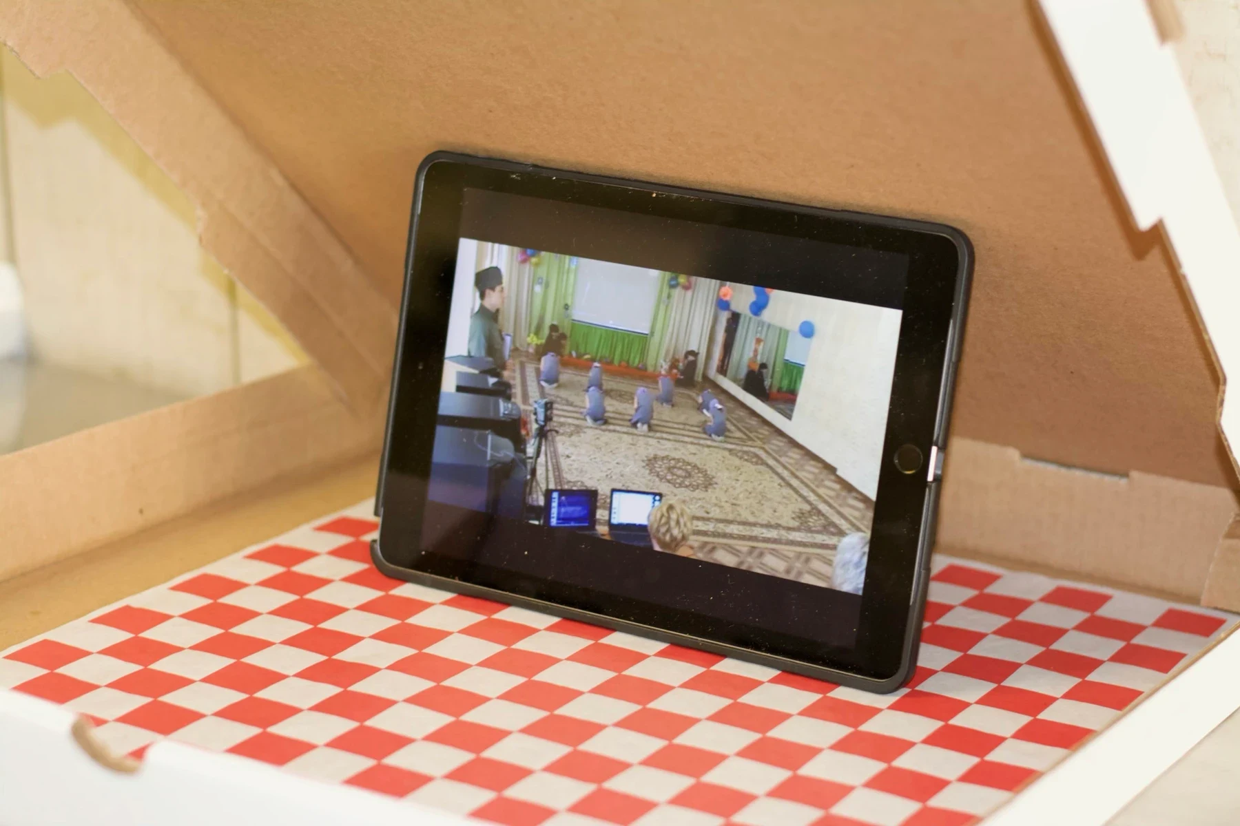 A tablet showing a video on a red and white checked surface.